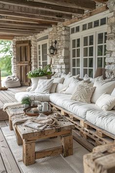 an outdoor living area with white couches and pillows on the outside porch, surrounded by wooden pallets