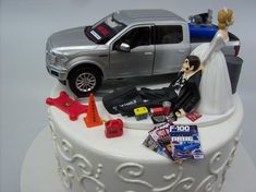 a wedding cake with a silver truck and bride and groom figurines