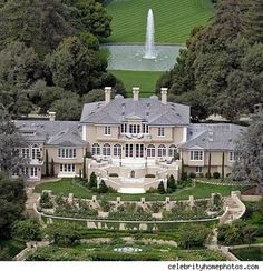 an aerial view of a large mansion in the middle of some trees and water fountain