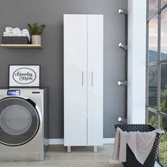 a washer sitting next to a window in a room with gray walls and white cabinets