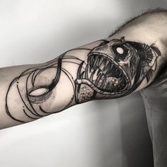 a man with a tattoo on his arm has a fish in it's mouth