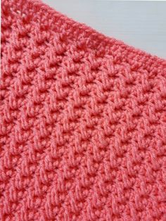 a pink crocheted blanket sitting on top of a table