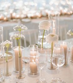 there are many vases with flowers and candles on the table