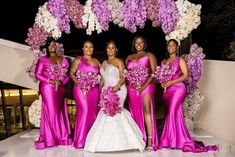 a group of women standing next to each other in front of a flower covered archway