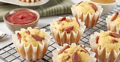 several muffins on a cooling rack with jam in the bowl next to them