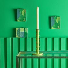 a white candle is sitting on a green table