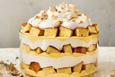 a yellow and white layered cake with frosting on top, sitting on a table