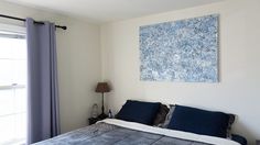 a bedroom with a large painting on the wall above the bed and blue pillows in front of it