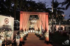 an outdoor wedding venue decorated with lights and flowers on the aisle, surrounded by palm trees