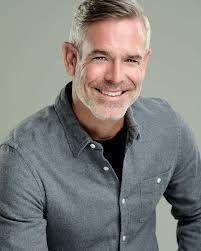 a man with white hair and beard smiling at the camera