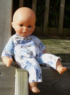 a baby doll sitting on top of a wooden fence