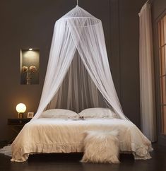 a white canopy bed in a bedroom next to a window