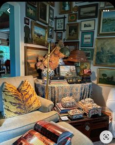 a living room filled with lots of furniture and pictures on the wall next to a lamp