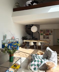 a living room filled with furniture next to a spiral stair case and table on top of a hard wood floor