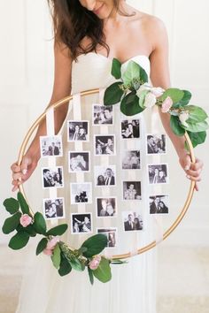 a woman is holding a wreath with photos on it and greenery around the frame