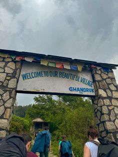 several people walking under a welcome sign