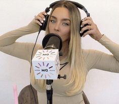 a woman sitting in front of a microphone with headphones on her ears and wearing a tan top