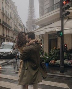 a man and woman kissing on the street in front of the eiffel tower