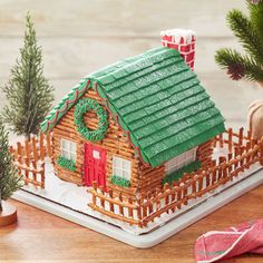 a gingerbread house decorated for christmas with decorations on the roof and fence around it