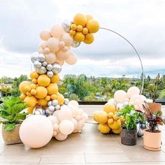 an arch made out of balloons and flowers on a table in front of a window