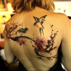 the back of a woman's shoulder with flowers and birds painted on her body