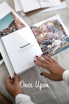 a person holding an open book on top of a table with pictures and text over it