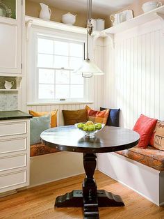 a kitchen with white cabinets and wood flooring next to a breakfast nook area