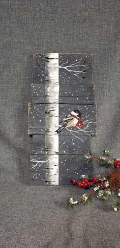 a bird sitting on top of a piece of wood next to berries and pine cones