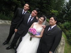 a group of people standing next to each other in front of some trees and bushes