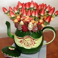 a watermelon shaped like a teapot with strawberries and chocolates in it