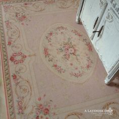 an old rug with flowers on it is next to a white cabinet and drawers in a room