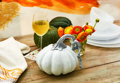 a white pumpkin sitting on top of a wooden table next to a glass of wine