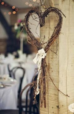 a heart shaped decoration hanging from the side of a wooden post at a wedding reception