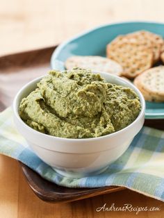 a white bowl filled with green dip next to crackers