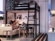 a man laying on top of a couch under a bunk bed next to a lamp