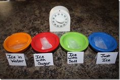 four different colored bowls sitting on top of a counter next to a timer and magnets