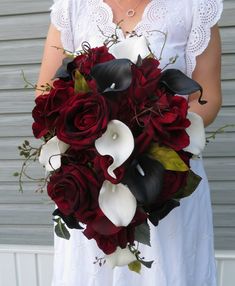 a bride holding a bouquet of red roses and calla lilies