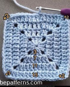 a crocheted square with numbers on the side and two holes in the middle