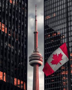 the canadian flag is flying in front of some tall buildings