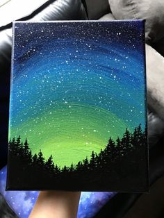 someone is holding up a painting with the stars in the night sky and trees on it