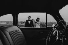 a bride and groom standing in the back seat of a car