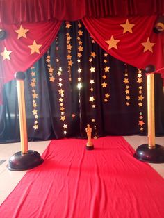 a red carpet with gold stars on it and two black poles in front of the curtain