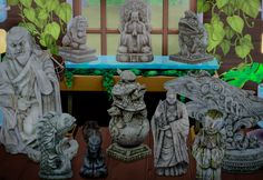 there are many statues on the table in front of a window with green plants behind it