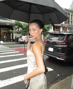 a woman walking down the street while holding an umbrella