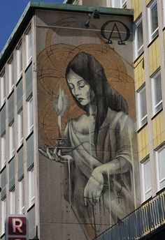 a large mural on the side of a building with a woman holding a lit candle