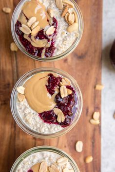 three jars filled with oatmeal and nuts on top of a wooden table