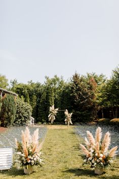 an outdoor ceremony set up with chairs, flowers and greenery in the foreground