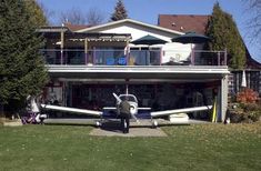 an airplane is parked in front of a large house with balconies on the roof