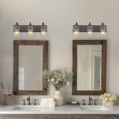 two bathroom sinks with mirrors above them and flowers in vases on the counter top