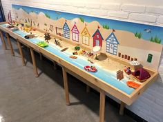 a long table that has some toys on it and is painted with beach scenes in the background